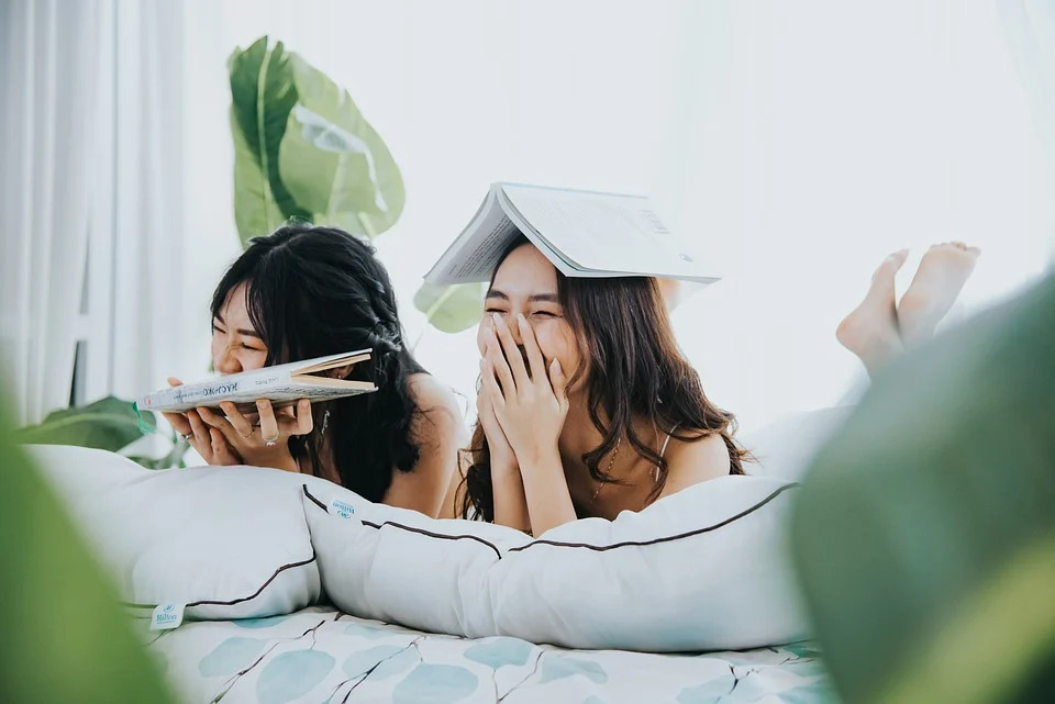 ベッドで寝転んで本を読んでいる２人の女性