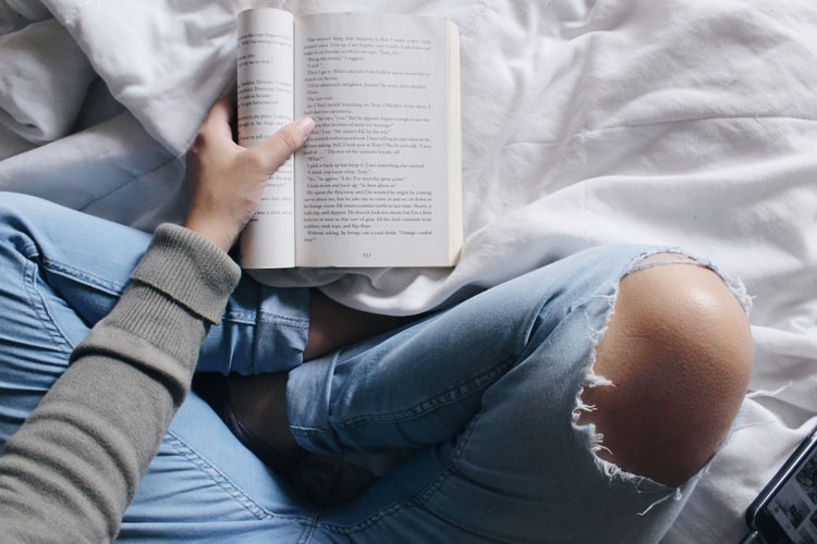 ベッドで座って本を読む女性