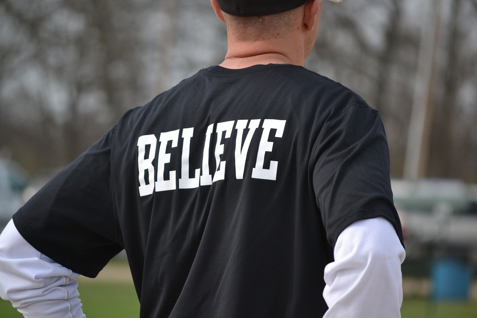 「BELIEVE」ロゴのシャツを着ている男性