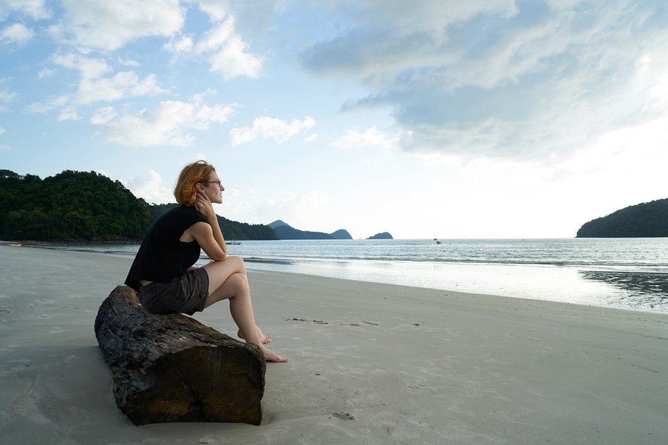 海辺に座って考え事をしている女性